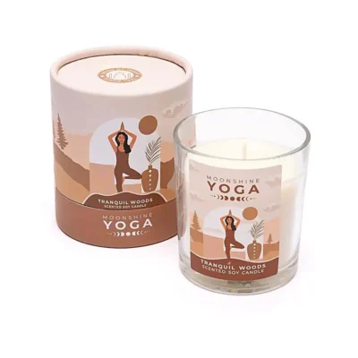 duftlys med brune nuancer og et etiket med en dame der laver yoga. lyset er i et glas